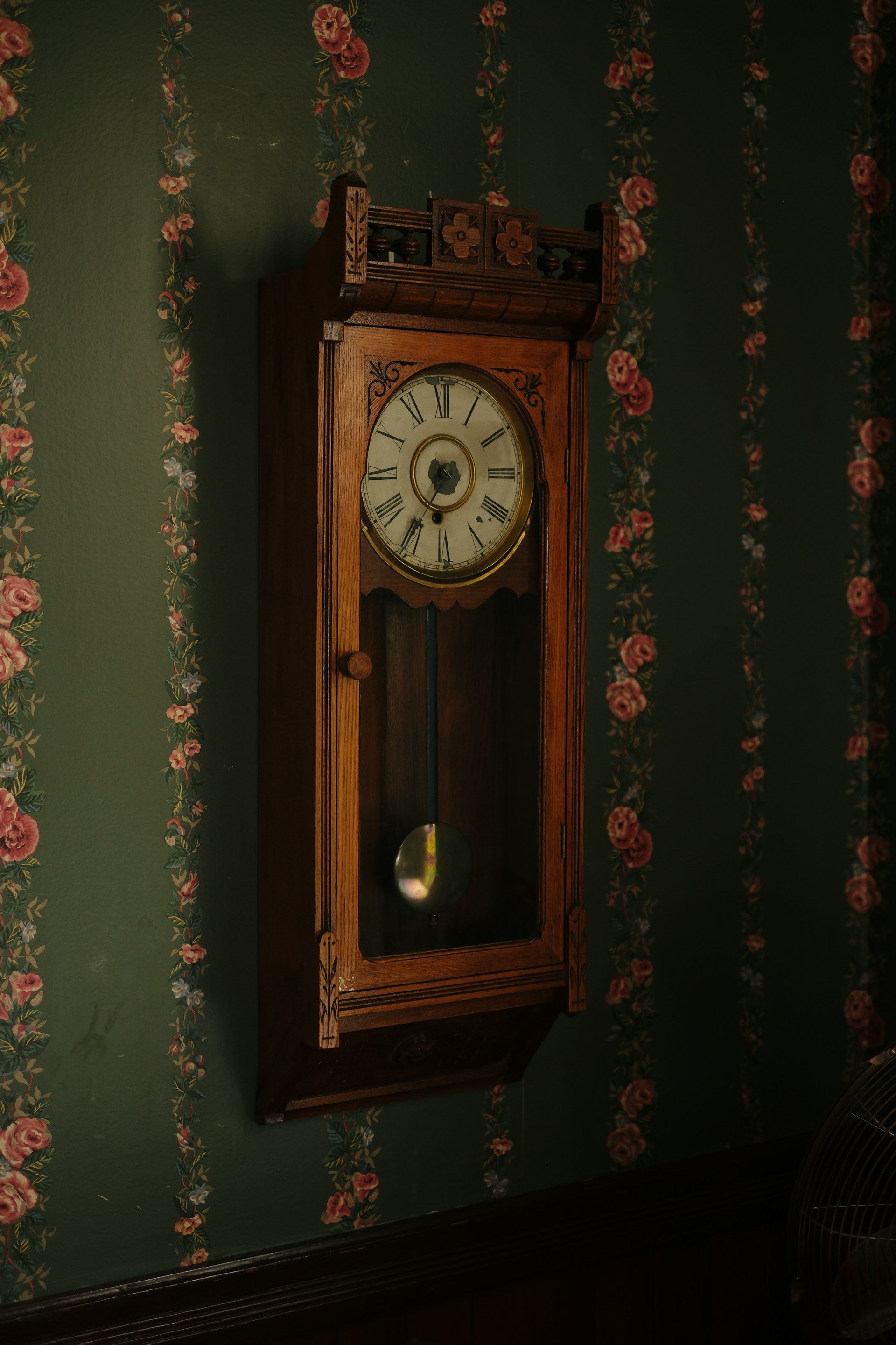 an old grandfather clock hanging on a green wall